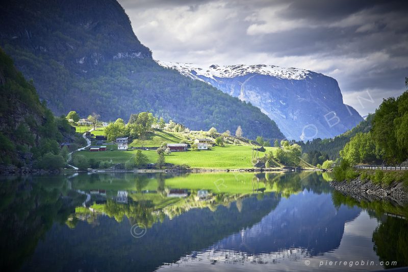 Majestueux fjord verdoyant en Norvege avec les reflets du village dans le lac